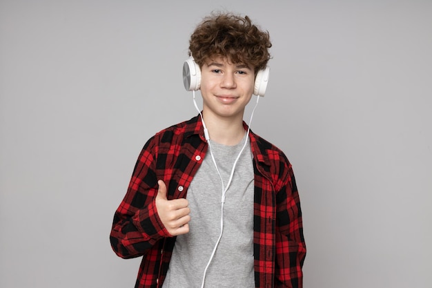 Adolescente chico atractivo en auriculares sobre fondo gris