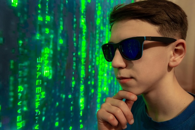 Un adolescente cibernético moderno con gafas contra el fondo de una matriz informática sostiene su barbilla cuando el código encriptado desaparece