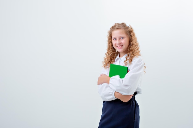 Adolescente colegial em uniforme escolar segurando um livro em um fundo branco