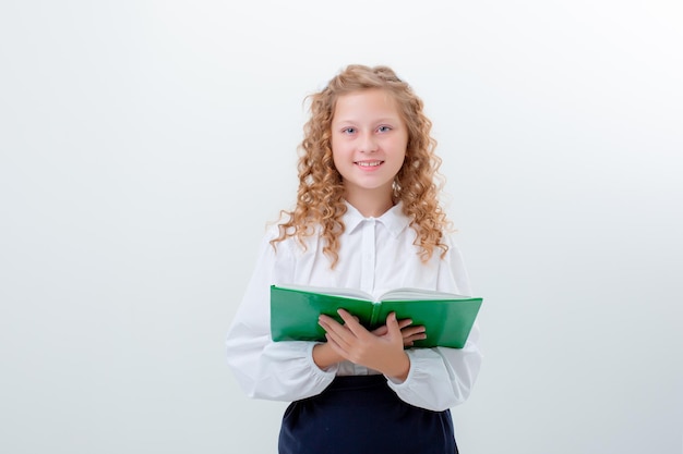 Adolescente colegial em uniforme escolar segurando um livro em um fundo branco