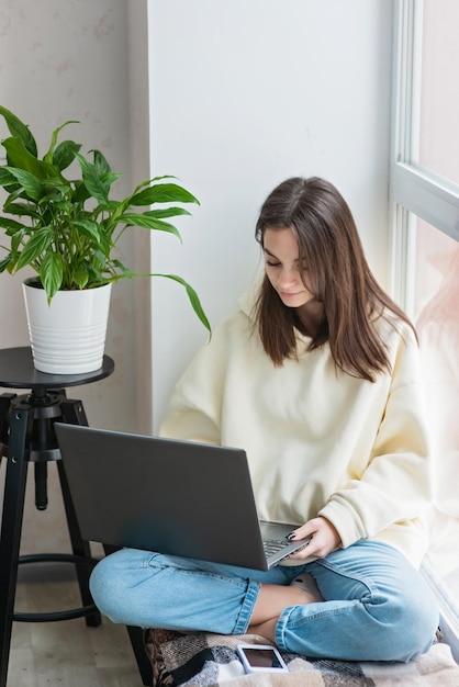 Adolescente colegiala alumna a distancia aprendiendo en línea en una clase virtual remota con un maestro por videoconferencia viendo una lección de reunión de zoom de seminario web en una computadora portátil en casa Enfoque selectivo suave