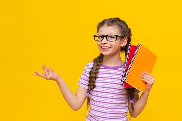 Una adolescente con coloridos cuadernos en las manos y anteojos Una niña se prepara para la escuela Cursos adicionales para el niño