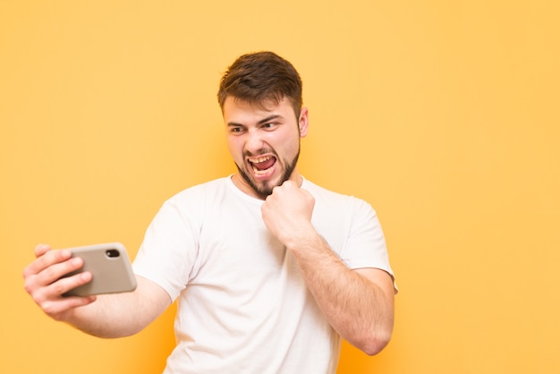 adolescente com barba joga videogame no smartphone e usa camiseta branca