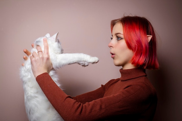 Adolescente com cabelo rosa segurando um gato branco em seus braços