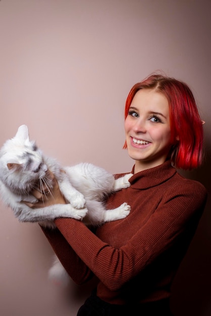 Adolescente com cabelo rosa segurando um gato branco em seus braços