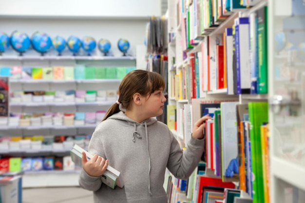 Adolescente com capuz cinza escolhendo livros na storexdxa