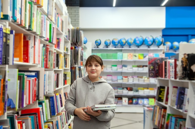 Adolescente com capuz cinza escolhendo livros na storexDxA