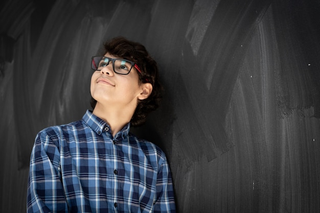 Adolescente com óculos em frente ao quadro-negro da sala de aula