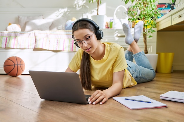 Adolescente com óculos estudando em casa usando um laptop