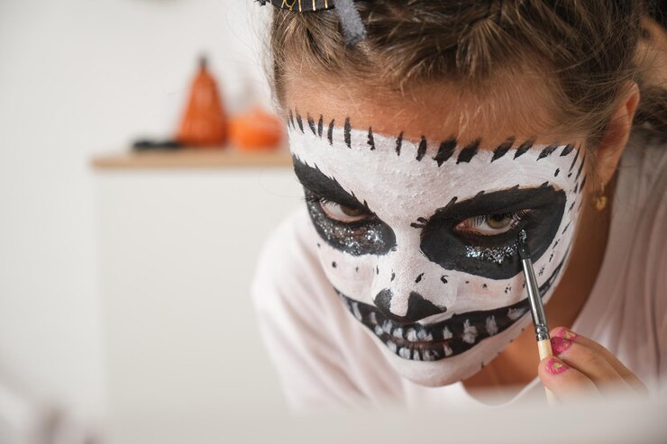 Foto adolescente com rosto pintado de halloween processo de desenho de crânio rosto pintado com brilho