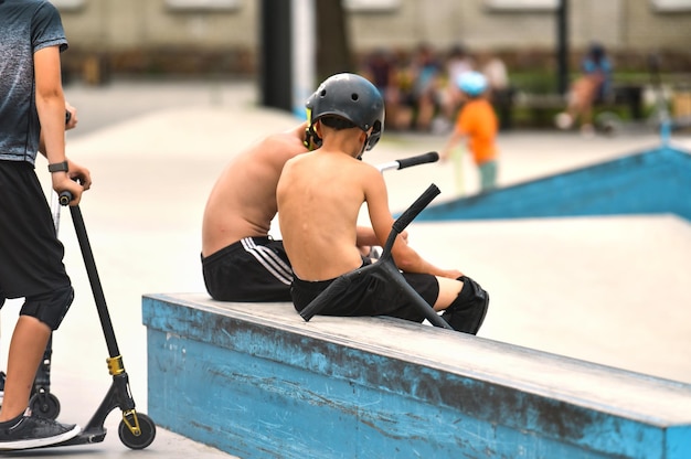 Adolescente com scooters no parque de skate. parque infantil público para um skate em um parque de recreação.