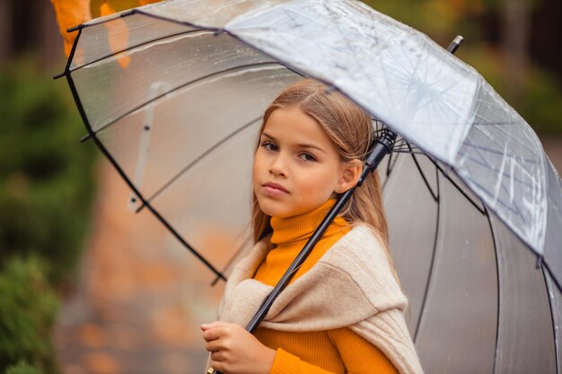 Adolescente com um guarda-chuva transparente em suas mãos em uma caminhada no outono em uma rua da cidade