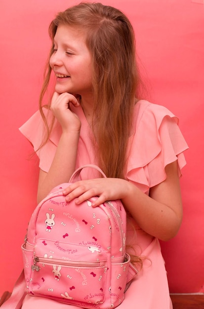 Foto adolescente com um vestido rosa e uma mochila rosa.