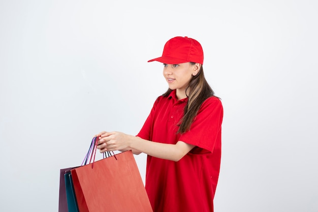 Adolescente com uniforme vermelho segurando sacolas de compras