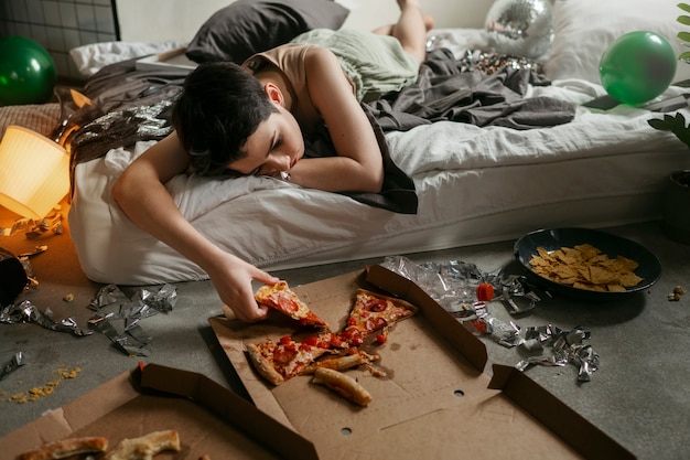 Adolescente comiendo pizza para reducir el efecto de la resaca