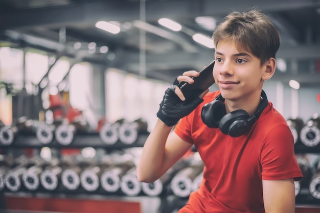 Adolescente comprometido en un gimnasio hablando por teléfono