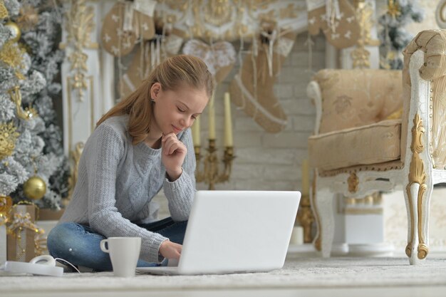 adolescente, con, computador portatil, en, piso, en, navidad