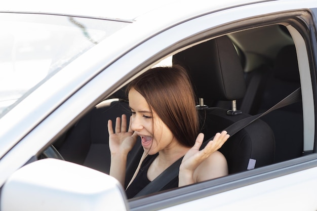 La adolescente conduce un automóvil por primera vez. Tiene miedo de conducir un automóvil. Agita las manos y grita.