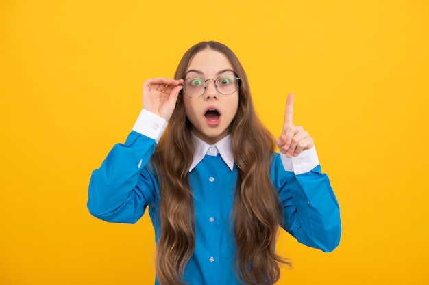 Una adolescente conmocionada con anteojos tuvo una idea genial manteniendo el dedo levantado con un fondo amarillo inteligente