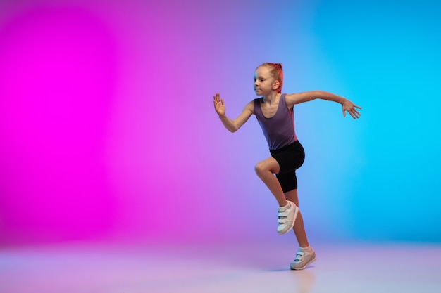 Adolescente correndo, correndo contra o fundo gradiente do estúdio de néon rosa-azul em movimento