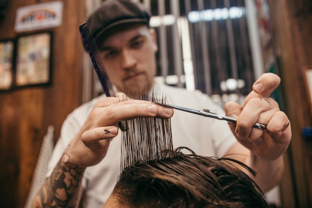 Foto adolescente corta o cabelo de cabeleireiro na barbearia. penteado retrô elegante na moda. retrato de uma criança com um lindo corte de cabelo. rússia, sverdlovsk, 12 de fevereiro de 2019