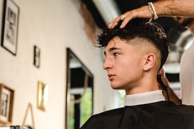 Adolescente, cortando o cabelo moderno em uma barbearia vintage