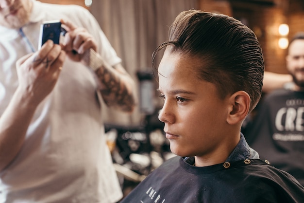 Foto adolescente cortes de pelo peluquería en la peluquería. peinado retro con estilo de moda