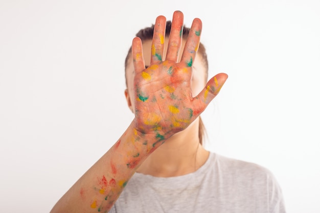 Adolescente cubre su rostro con su palma izquierda en pintura
