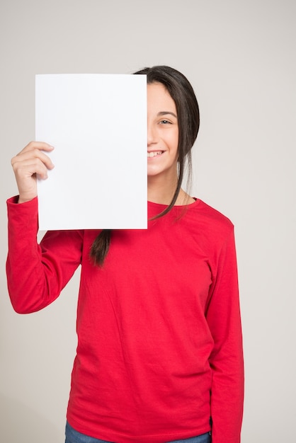 Foto adolescente cubriendo la mitad de su cara con una hoja de papel