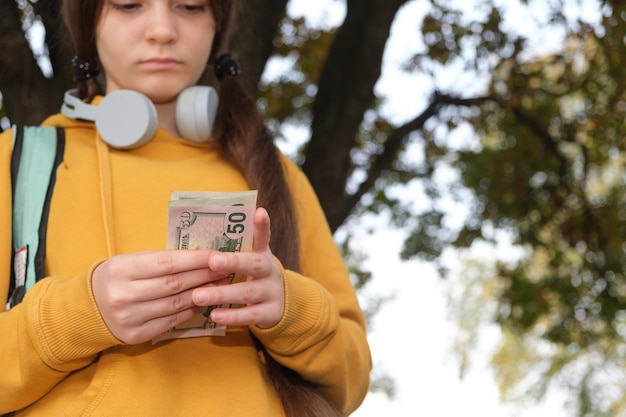 Adolescente cuenta billetes de dólar con lugar para texto