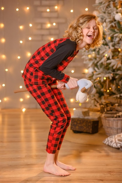 Adolescente de pijama vermelho ri com um brinquedo nas mãos. no estúdio para o ano novo.