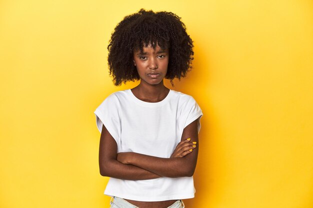 Adolescente de tanque branco com fundo amarelo de estúdio, infeliz a olhar para a câmara.