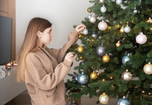 Adolescente decora el árbol de Navidad. Árbol de Navidad en la sala de estar.