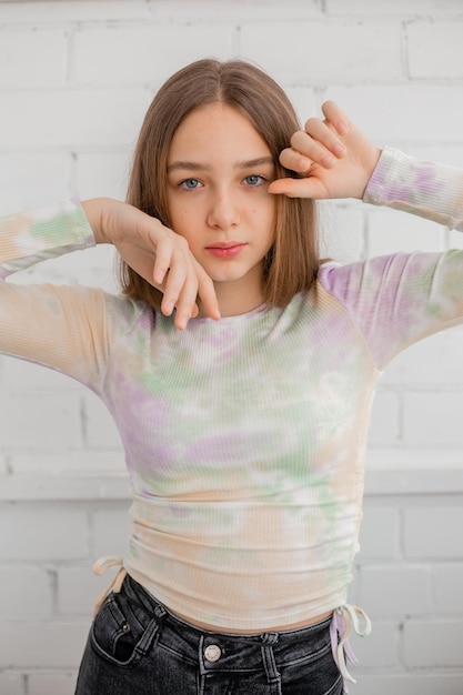 Una adolescente delgada con jeans y cuello alto posa contra una pared de ladrillo blanco. belleza natural, sin maquillaje, iluminación natural. espacio para texto. foto de alta calidad