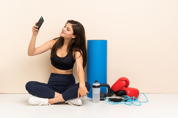 Adolescente deporte niña sentada en el piso haciendo una selfie