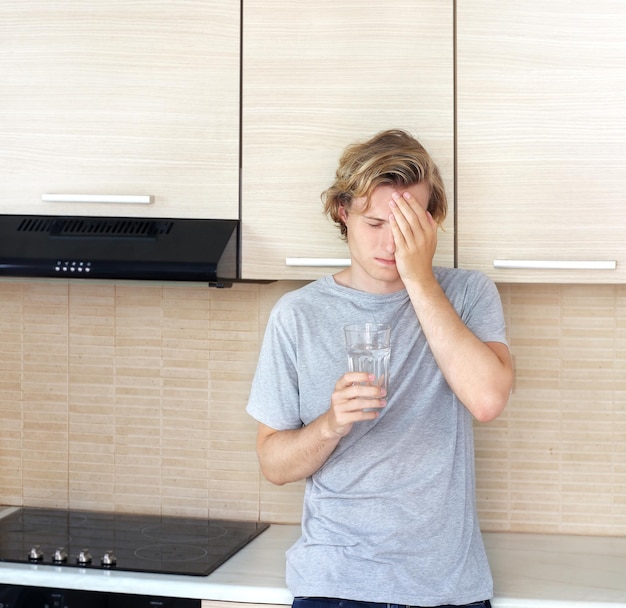 Adolescente deprimido de pie en la cocina