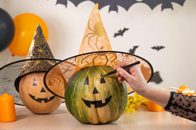 Adolescente desenhando rosto assustador e engraçado de Jack O Lantern na abóbora com caneta preta para o Halloween