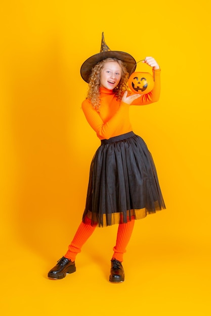 Adolescente en un disfraz de bruja sobre un fondo amarillo halloween