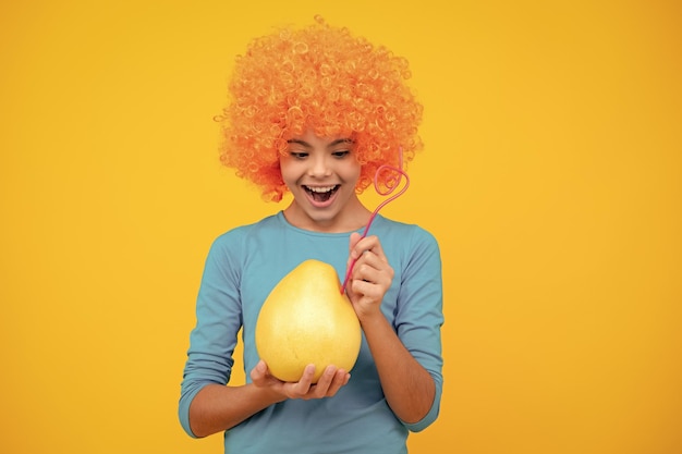 Una adolescente divertida sostiene un pummelo de cítricos o un pomelo verde grande aislado en un fondo amarillo Retrato de una adolescente feliz Niña sonriente