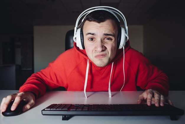 Adolescente divertido Por la noche disfrutar de una computadora en casa. El chico mira de cerca el monitor.