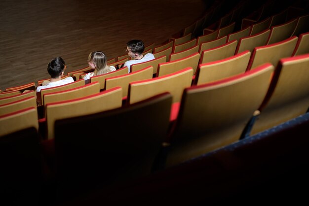 Adolescente e dois meninos sorrindo vendo um filme em um cinema