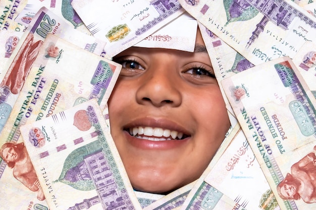 Un adolescente egipcio cubierto con dinero egipcio en la denominación de 200 libras
