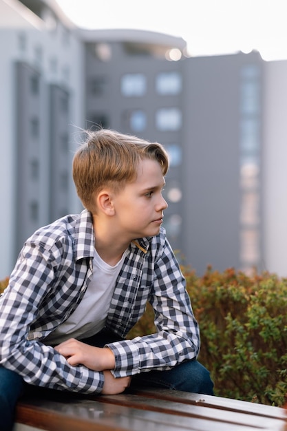 Adolescente elegante em roupas casuais está relaxando ao ar livre sentado em um banco de parque