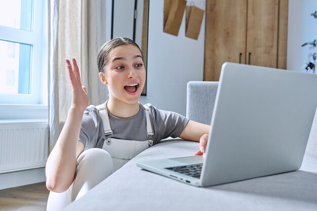 Adolescente em casa no sofá usando laptop falando emocionalmente