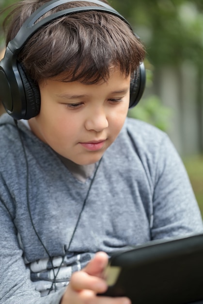 Adolescente em fones de ouvido ao ar livre, ouvir música ou assistir vídeo no tablet PC