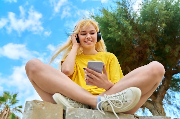 Adolescente em fones de ouvido olhando no smartphone