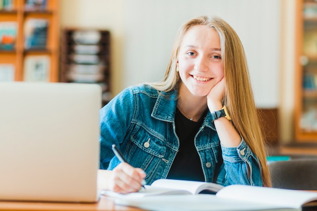 Adolescente encantador sonriendo y tomando notas