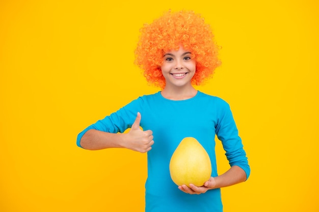 Adolescente engraçada segura pomelo de frutas cítricas ou toranja grande pomelo isolada em fundo amarelo Frutas de verão Retrato de adolescente feliz Garota sorridente