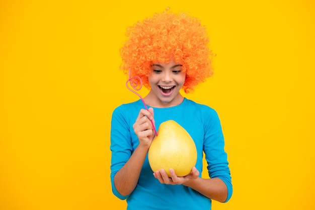 Adolescente engraçada segura pomelo de frutas cítricas ou toranja verde grande pomelo isolada em fundo amarelo Retrato de adolescente feliz Garota sorridente