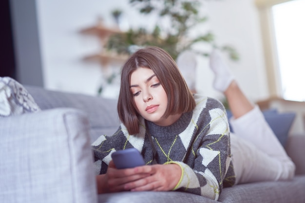 adolescente enviando mensajes de texto en casa